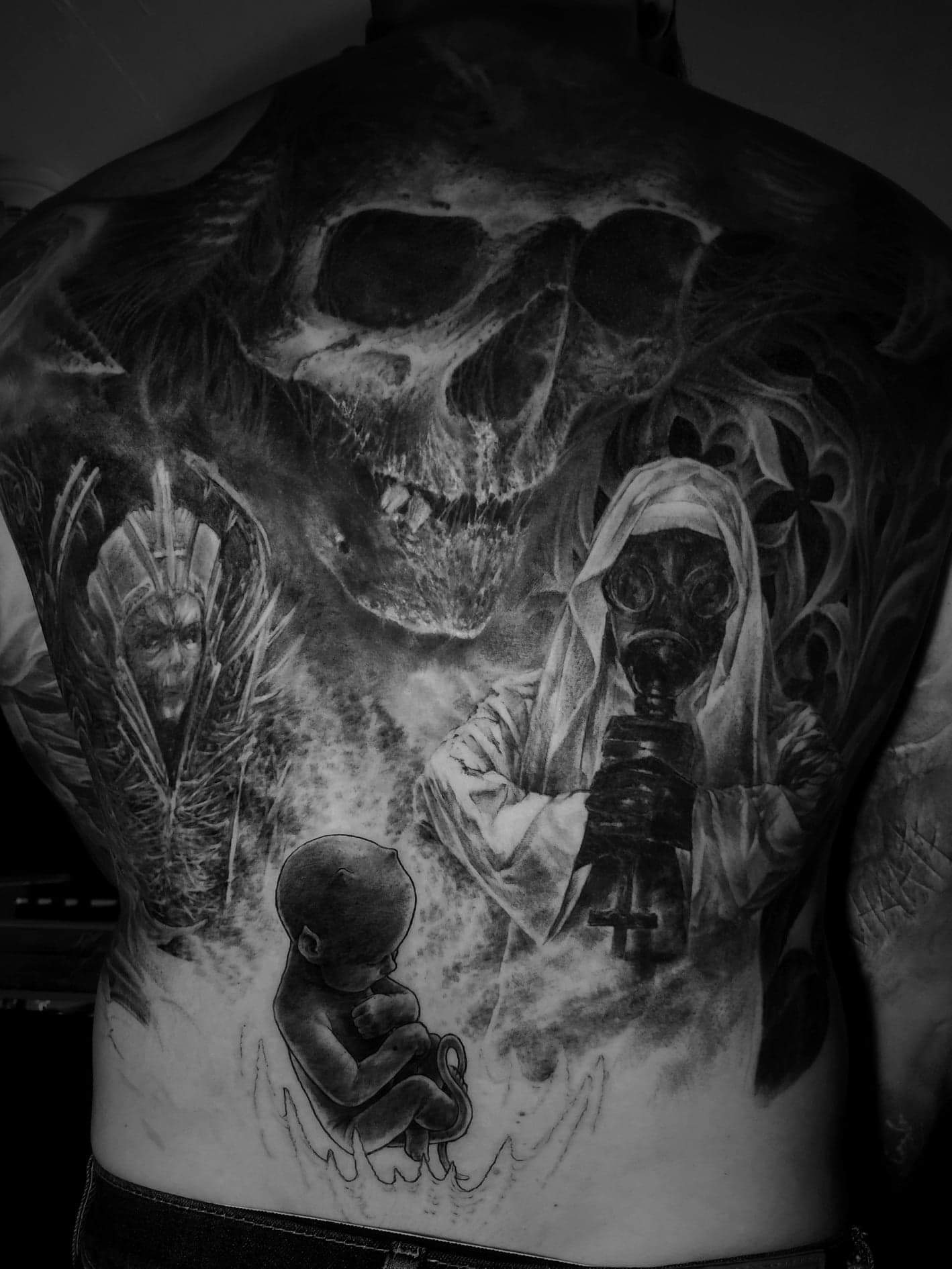 Tatouage dark art dos complet - crane, figure au masque a gaz et silhouettes sombres, realise par Nicko chez Physical Design Morges